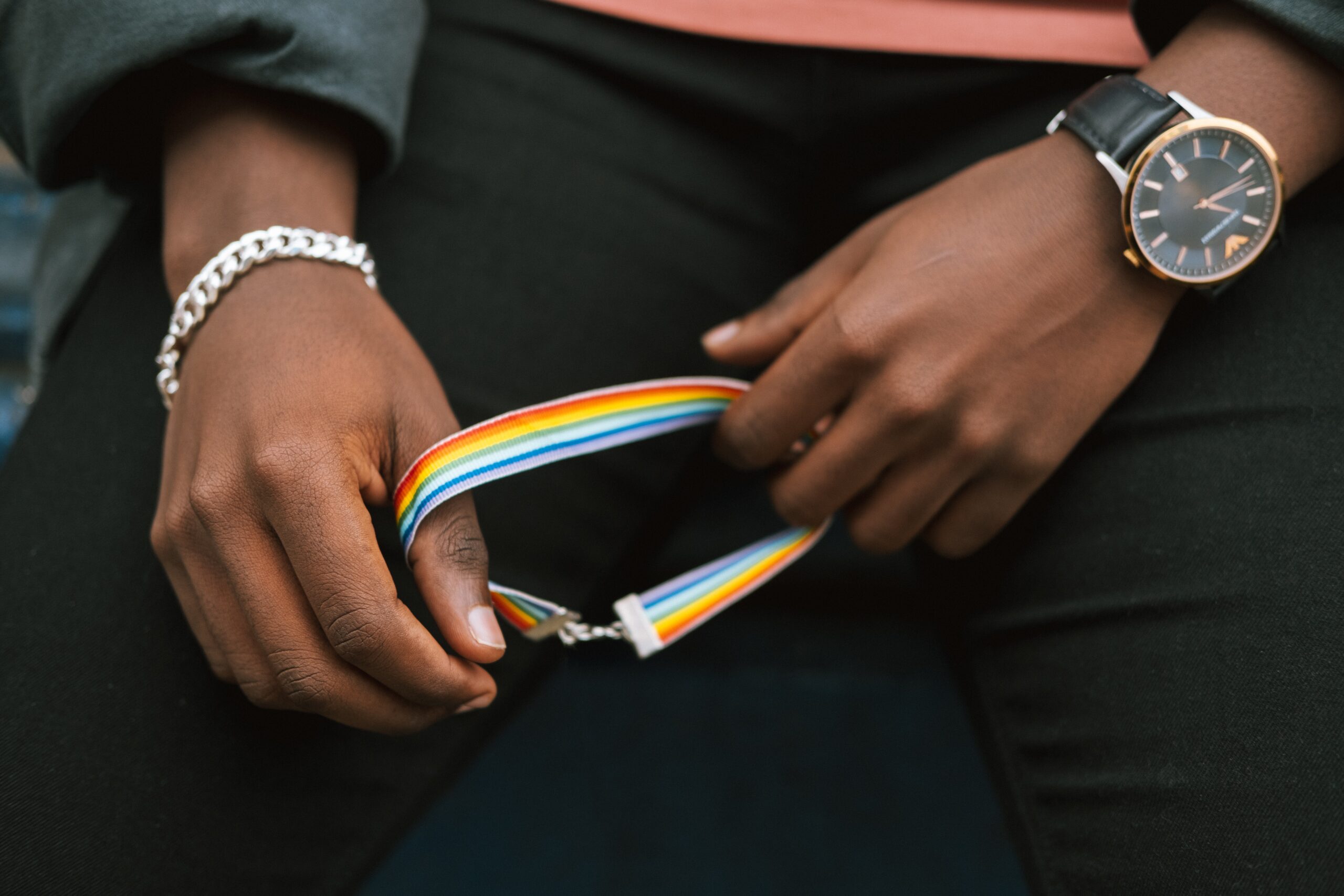 A person holding an LGBTQ bracelet