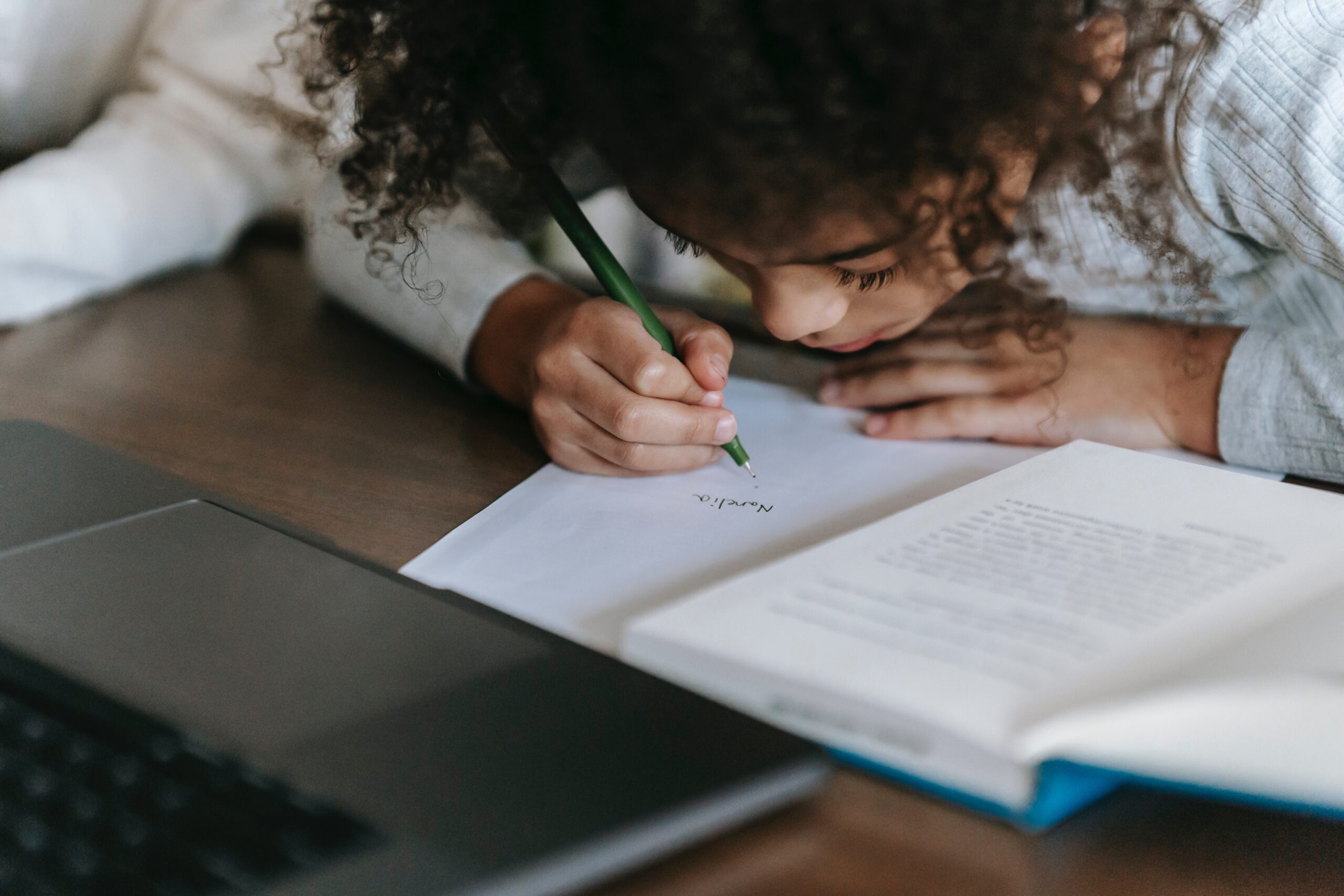 Child taking notes from a computer